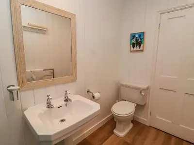 a bathroom with a sink and a toilet and a mirror at Valetta, Thorpeness in Thorpeness