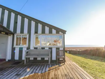 a house with a bench on a wooden deck at Valetta, Thorpeness in Thorpeness