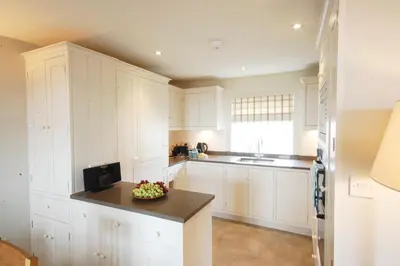 a kitchen with white cabinets and a bowl of fruit on a counter at Crabbe House in Aldeburgh