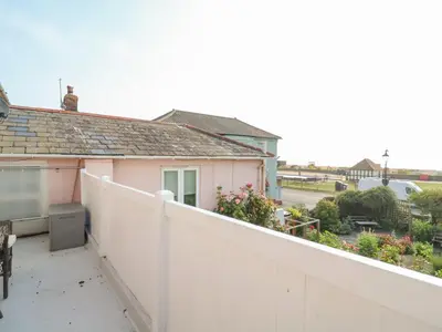 a balcony with a white fence and a pink house at Crabbe House in Aldeburgh