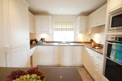 a kitchen with white cabinets and a bowl of fruit at Crabbe House in Aldeburgh
