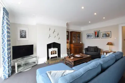 a living room with a blue couch and a fireplace at Regatta Lookout in Aldeburgh