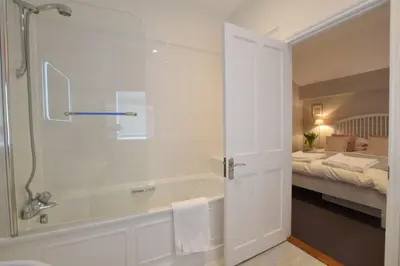 a bathroom with a bath tub and a bedroom at Regatta Lookout in Aldeburgh