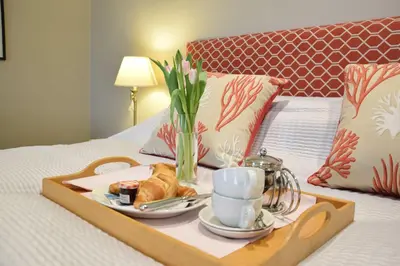 a tray with food and coffee and croissants on a bed at Regatta Lookout in Aldeburgh