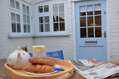a table with a plate of pastries and a tea pot at Vesta Cottage, Orford in Orford