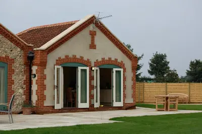 a brick house with a patio and a table at Romulus in Roudham