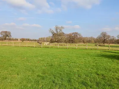 a field of green grass with a wooden fence at Romulus in Roudham