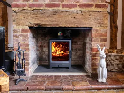 a brick fireplace with a stove in it at Wassicks Cottage, Haughley in Haughley