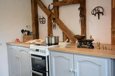 a kitchen with white cabinets and a stove top oven at Wassicks Cottage, Haughley in Haughley