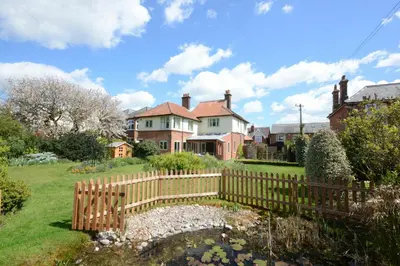 a house with a wooden fence in a yard at Holly Lodge in Aldeburgh