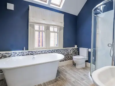 a blue bathroom with a tub and a toilet at Holly Lodge in Aldeburgh