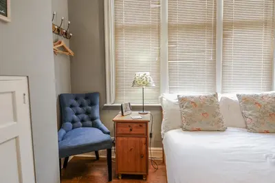 a bedroom with a bed and a blue chair at Holly Lodge in Aldeburgh