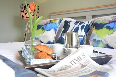 a breakfast tray with croissants and newspapers on a bed at Bunny Cottage, Aldeburgh in Aldeburgh