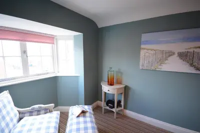 a blue room with a couch and a window at Bunny Cottage, Aldeburgh in Aldeburgh