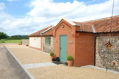 a brick house with a green door and a cat sitting outside at Remus in Larling
