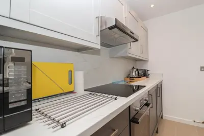 a kitchen with white cabinets and a yellow appliance at Holmleigh, Aldeburgh in Aldeburgh