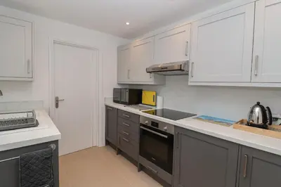 a kitchen with white cabinets and a stove top oven at Holmleigh, Aldeburgh in Aldeburgh