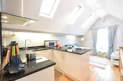 a kitchen with white cabinets and a black counter top at Pied a Mer, Aldeburgh in Aldeburgh