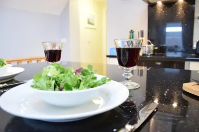 a table with a bowl of salad and two glasses of wine at Pied a Mer, Aldeburgh in Aldeburgh
