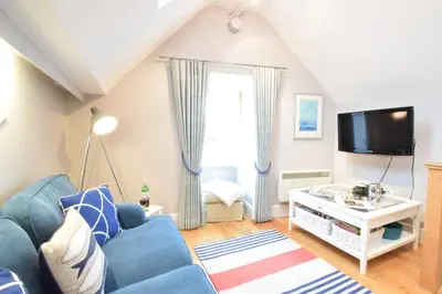 a living room with a blue couch and a tv at Pied a Mer, Aldeburgh in Aldeburgh