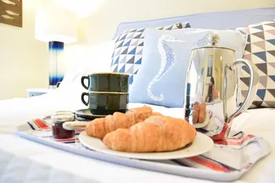 a tray with bread and coffee on a bed at Pied a Mer, Aldeburgh in Aldeburgh