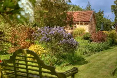 a bench in front of a garden with a house at Chobbs Barn, Eye in Eye