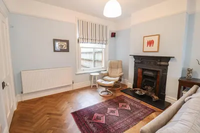 a living room with a fireplace and a chair at Lavender House, Aldeburgh in Aldeburgh
