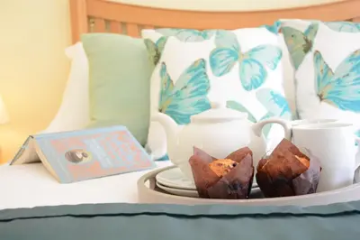 a tray with cups and a tea set on a bed at Seafarers in Fressingfield