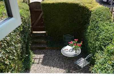 a garden with a table with a vase of flowers on it at Seafarers in Fressingfield