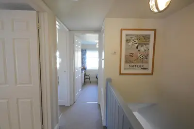 a hallway with a staircase with a picture on the wall at Pebble Beach Cottage, Aldeburgh in Aldeburgh