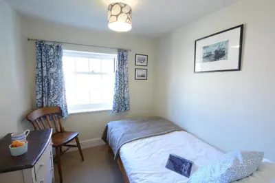 a bedroom with a bed and a desk and a window at Pebble Beach Cottage, Aldeburgh in Aldeburgh