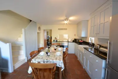 a kitchen with a table and chairs and a kitchen with white cabinets at Pebble Beach Cottage, Aldeburgh in Aldeburgh