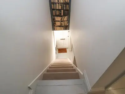 a staircase in a house with books on the wall at Mariners Cottage in Aldeburgh