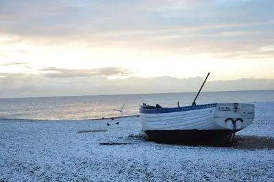 a boat sitting on the shore of a beach at Mariners Cottage in Aldeburgh