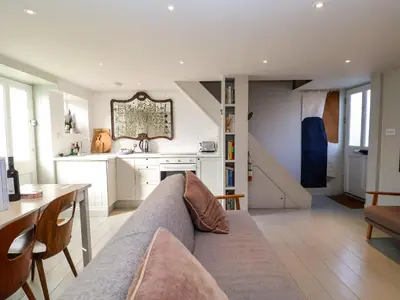 a living room with a couch and a table and a kitchen at Mariners Cottage in Aldeburgh