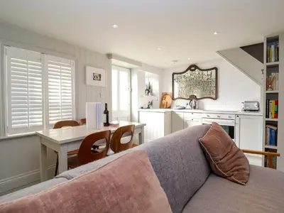 a living room with a couch and a table in a kitchen at Mariners Cottage in Aldeburgh