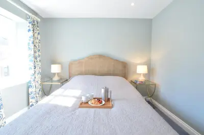 a bedroom with a bed with a tray of food on it at Seawall Cottage, Aldeburgh in Aldeburgh