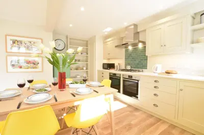 a kitchen with a wooden table and yellow chairs at Seawall Cottage, Aldeburgh in Aldeburgh