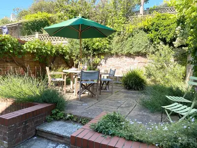 a patio with a table and a green umbrella at Seawall Cottage, Aldeburgh in Aldeburgh