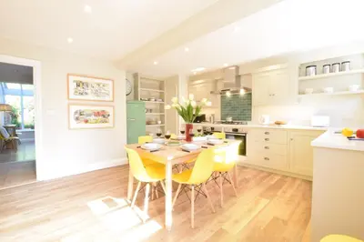 a kitchen and dining room with a table and yellow chairs at Seawall Cottage, Aldeburgh in Aldeburgh