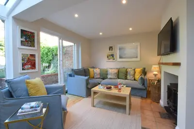 a living room with a blue couch and a table at Seawall Cottage, Aldeburgh in Aldeburgh