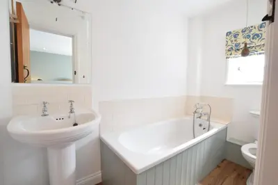 a white bathroom with a sink and a tub at Seawall Cottage, Aldeburgh in Aldeburgh