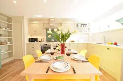 a kitchen with a wooden table and yellow chairs at Seawall Cottage, Aldeburgh in Aldeburgh