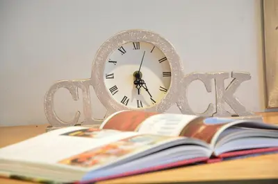 a clock sitting on a table next to a book at 1 Grange Cottages, Westleton in Westleton