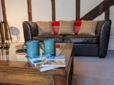 a living room with a leather couch and a coffee table at Lavender Cottage, Aldeburgh in Aldeburgh