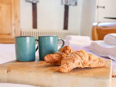 two cups and croissants on a wooden cutting board at Lavender Cottage, Aldeburgh in Aldeburgh