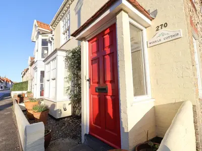 a red door on the side of a house at Winkle Cottage, Aldeburgh in Aldeburgh