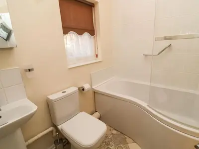 a white bathroom with a toilet and a bath tub at Winkle Cottage, Aldeburgh in Aldeburgh