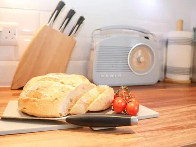 a loaf of bread on a cutting board with a knife and tomatoes at Saffron, Blythview in Blythburgh