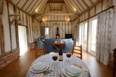 a dining room with a table in a barn at Bird Cottage, Burgh in Grundisburgh